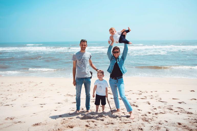 Familie bestehend aus Mann, Frau und zwei Kindern am Strand.