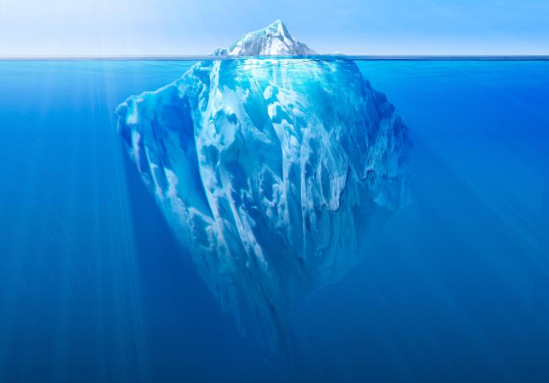 Ein Eisberg ist zu sehen, dessen größter Teil unter der Wasseroberfläche liegt.