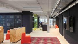 Büroflur mit Blick in die Büros, modernes Design, Teppiche und bunte Farben.