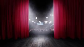 Bild des sich öffnenden roten Vorhangs auf einer Theaterbühne.