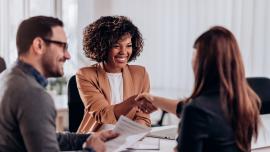 Einer Frau wird von zwei Recruitern zum erfolgreichen Bewerbungsgespräch gratuliert.