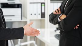 Man sieht in Nahaufnahme eine ausgestreckte Hand und die verschränkten Arme einer anderen Person.