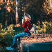 Frau sitzt im Wald und fotografiert.