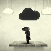 Ein Schwarz-weiß-Bild von einer Person mit Regenschirm, die unter einer schwarzen Wolke steht. Rechts und links der schwarzen Wolke befinden sich je zwei weiße Wolken.