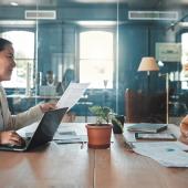 Zwei Businessfrauen sitzen sich an einem Arbeitstisch im Office gegenüber