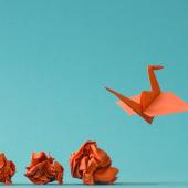 4 zerknüllte Papiere und ein  Origami-Kranich