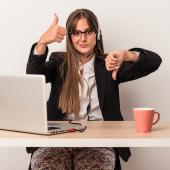 Eine junge Frau sitzt an einem Laptop und streckt einen Daumen nach oben und einen nach unten.