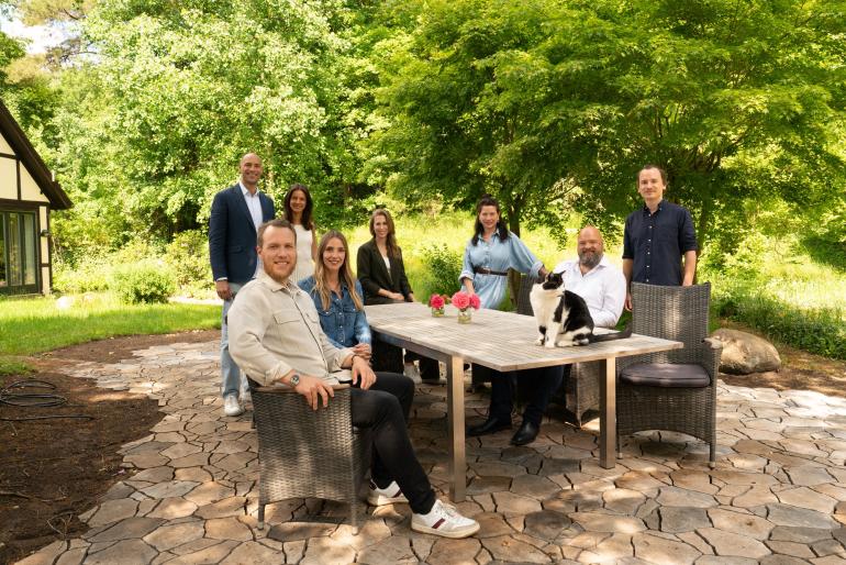 Das Team von Wolf & Adler sitzt an einem Tisch im Grünen