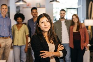 Eine Frau steht zufrieden vor ihrem Team