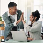 Ein Mann gibt einer Frau im Büro ein anerkennendes High Five