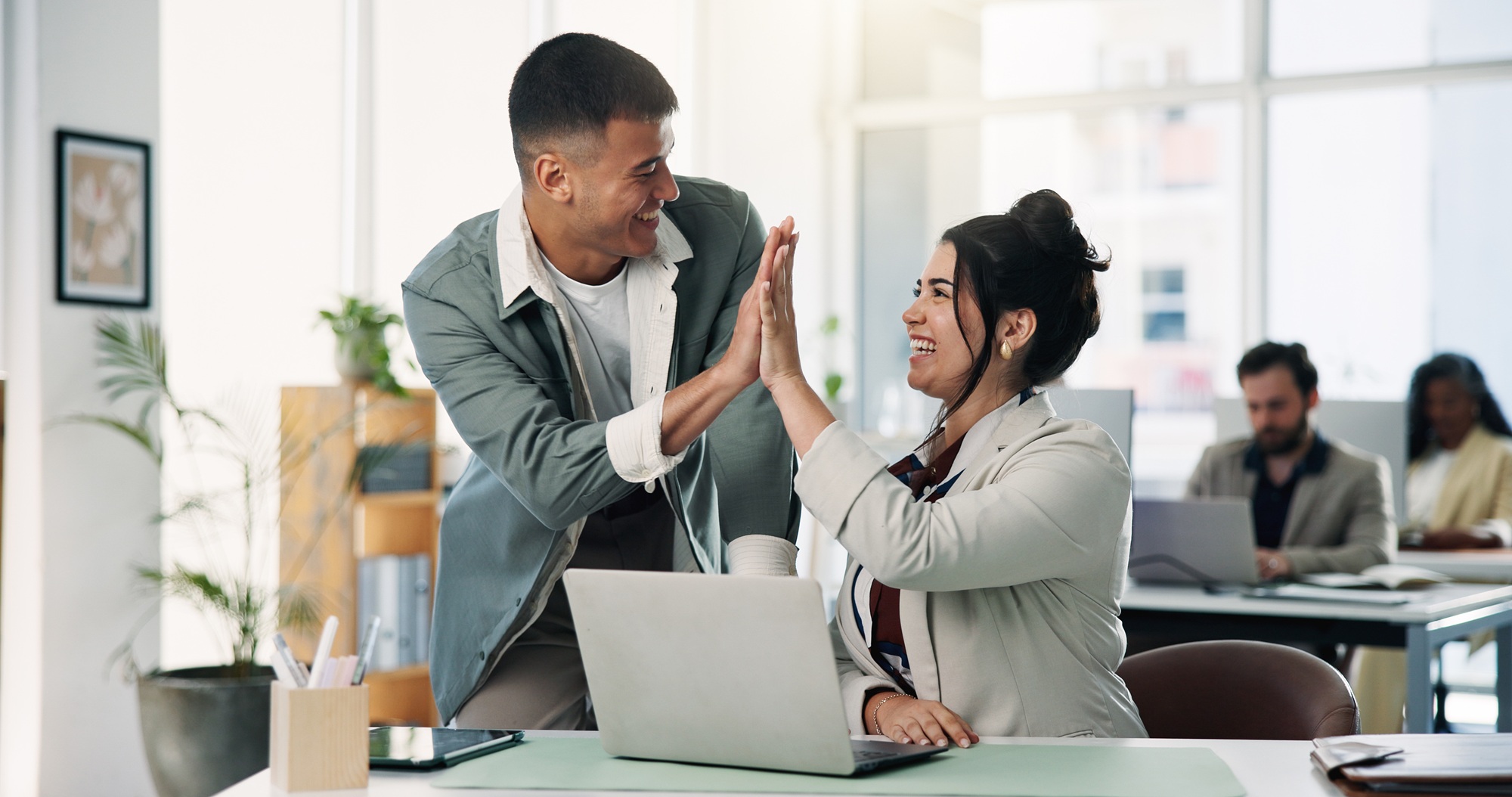 Ein Mann gibt einer Frau im Büro ein anerkennendes High Five