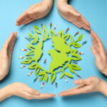 Sechs Hände bilden einen Kreis um eine grüne Zeichnung der Erde.