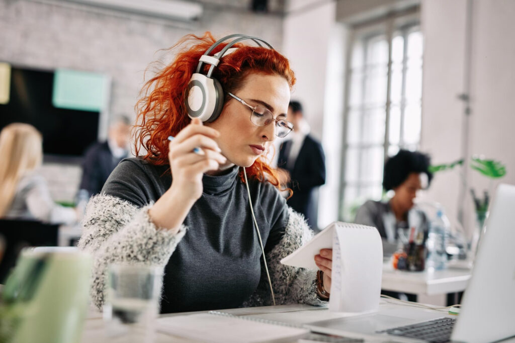Eine junge Frau mit Noise-Cancelling-Kopfhörern im Büro.