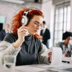 Eine junge Frau mit Noise-Cancelling-Kopfhörern im Büro.