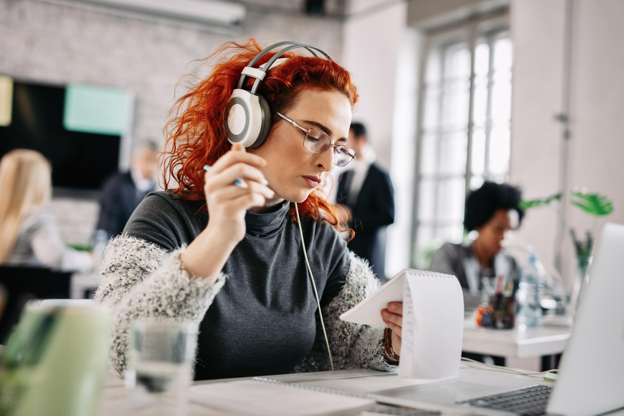 Eine junge Frau mit Noise-Cancelling-Kopfhörern im Büro.